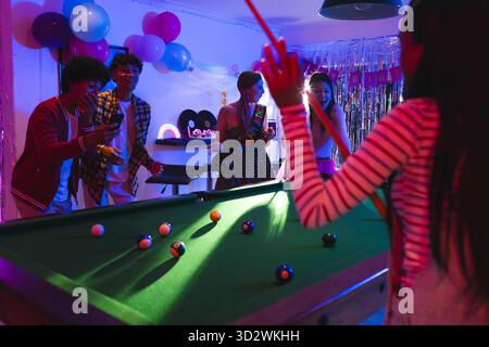 Billard spielen und tanzen, Teenager feiern eine lebhafte Geburtstagsparty mit Freunden. Feier, Unterhaltung, Gruppe, Soziales, Feste, Freundschaft || Model veröffentlicht Stockfoto