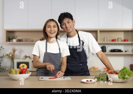 Ein glückliches Paar bereitet in einer modernen Küche Essen zu, wobei es ihre Teamarbeit und den Genuss gesunder Kochen zeigt Stockfoto