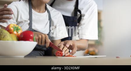 Ein Paar teilt einen zärtlichen Moment in der Küche, schneidet Gemüse und genießt die Gesellschaft des anderen beim Kochen Stockfoto