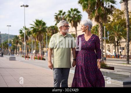 Seniorenpaar geht Hand in Hand auf der Stadtpromenade Stockfoto