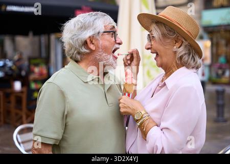Seniorenpaar teilt sich Eiskegel bei einem Date im Freien Stockfoto