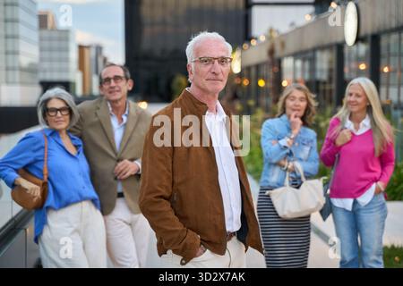Eine Gruppe eleganter Seniorenfreunde macht einen entspannten Spaziergang durch die Stadt, plaudert und verbringt gute Zeit miteinander Stockfoto