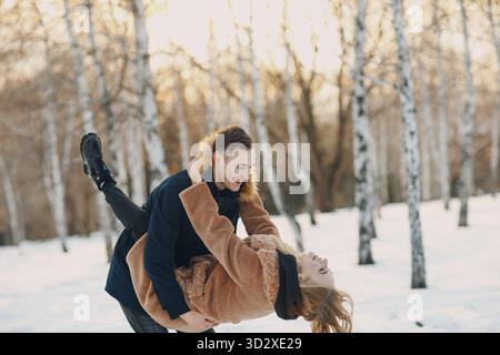 Liebe junge Paare, die sich umarmen und Spaß im Winterwald haben Stockfoto