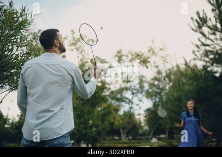 Junges erwachsenes Paar spielt Badminton im Park Stockfoto