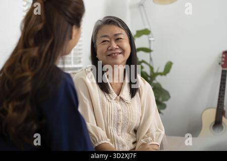 Eine Pflegekraft teilt einen freundlichen Moment mit einem älteren Patienten und fördert so das emotionale Wohlbefinden und das Vertrauen in die Wohnung. In der Einstellung wird die Kombi hervorgehoben Stockfoto