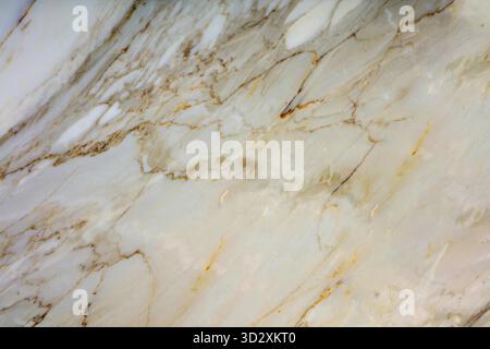Dies ist eine Nahaufnahme einer weißen Marmorstruktur mit goldenen und braunen Streifen. Die Streifen sind unregelmäßig und überall verstreut Stockfoto