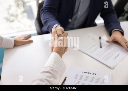 Junge männliche Geschäftspartner schütteln sich die Hände über den Papiervertrag Stockfoto