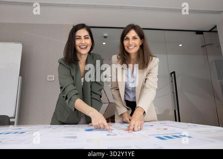 Two positive product manager women working together at meeting table Stockfoto