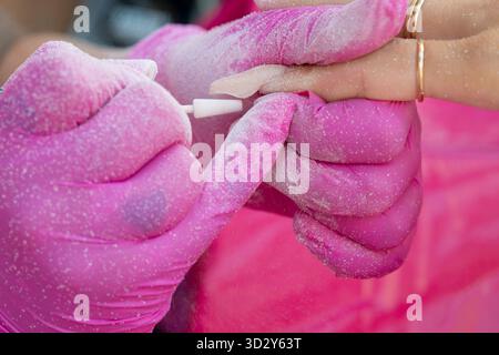 Frau im Salon erhält Maniküre durch Nagelverlängerung Stockfoto