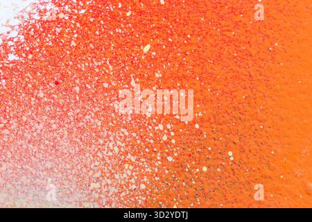 Makroaufnahme eines Wandsprays, das mit hellorange und rot mit weißem Spray lackiert ist. Abstrakter strukturierter, spritzender und farbenfroher Graffiti-Hintergrund. Stockfoto