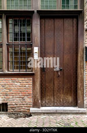 Antwerpen, Belgien - 23. August 2018 - historische Holztür mit Ziegeleinfassung und eisernem Kreuzgriff. Stockfoto