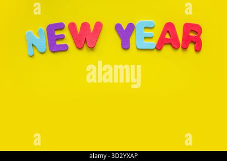 Happy New Year-Zeichen mit Buchstaben, isoliert auf gelbem Hintergrund mit Kopierraum. Flache Ladefläche mit Kopierraum. Stockfoto