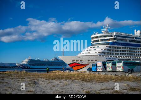 Ein großes Kreuzfahrtschiff namens AIDA Bella liegt im norwegischen Alta Harbor an, wobei das Kreuzfahrtschiff Emerald Princess im Hintergrund unter einem klaren Blau sichtbar ist Stockfoto