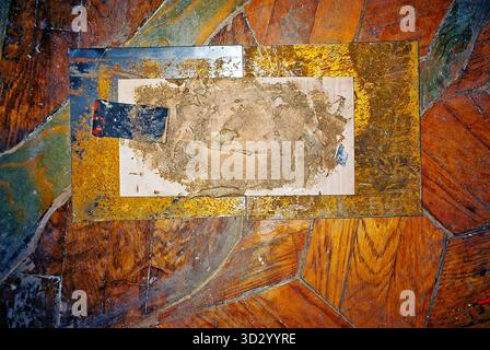 Rostige Metallplatten und Werkzeugmarken auf authentischem Parkett, aufgenommen in analogem Film mit Blitz, um Textur und Details hervorzuheben. Stockfoto