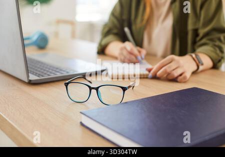 Nahaufnahme Einer Brille Auf Dem Tisch Mit Frau, Die Im Hintergrund Arbeitet Stockfoto
