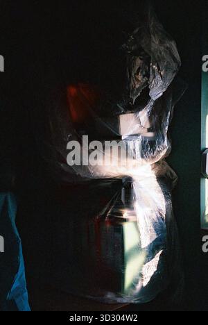 Regale mit Dokumenten und Büchern, die während der Renovierung und Malerei mit dünnem Kunststoff bedeckt sind, in sanften analogen Tönen gehalten. Stockfoto