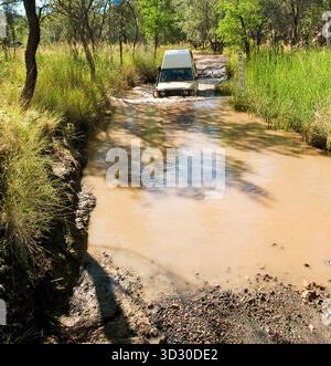 Ein Fahrzeug mit Allradantrieb überquert einen schlammigen Bach auf der zerklüfteten Zufahrtsstrecke zum Purnululu National Park (Bungle Bungle) in Western Australia Stockfoto