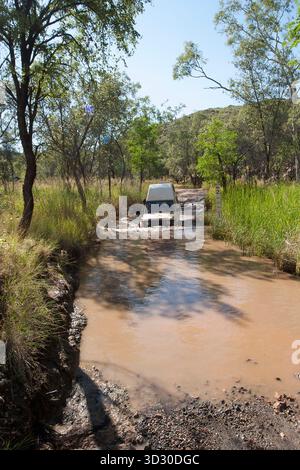 Ein Fahrzeug mit Allradantrieb überquert einen schlammigen Bach entlang der Zufahrtsstraße zur Bungle Bungle Range im Purnululu National Park, Western Australia Stockfoto
