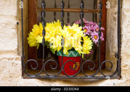 Fensterdekoration mit bunten Kunstblumen in Mdina, Malta. Stockfoto