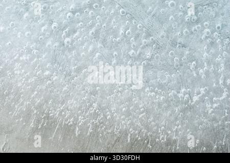 Frost entwickelt einzigartige, empfindliche Muster auf einer Glasoberfläche, die von innen betrachtet wird. Das Kunstwerk zeigt winzige Eisformationen und Blasen, die Licht reflektieren Stockfoto