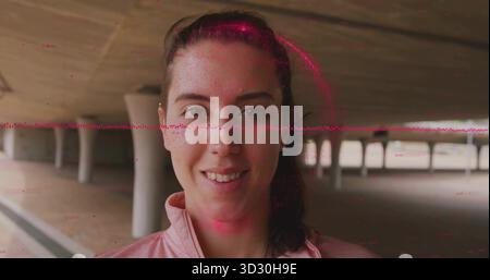 Stehende Frau mit rosa sportlicher Reißverschlussjacke in Betonunterführung mit roten Glitzerlinien Stockfoto