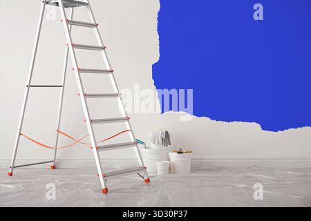 Trittleiter und verschiedene Werkzeuge im leeren Raum. Wand teilweise blau gestrichen. Innenrenovierung Stockfoto