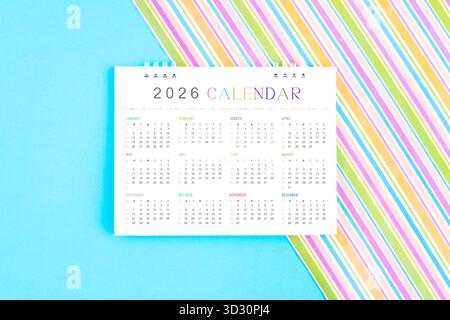2026 Schreibtischkalender auf farbenfrohem Hintergrund, Flat Lay. Stockfoto