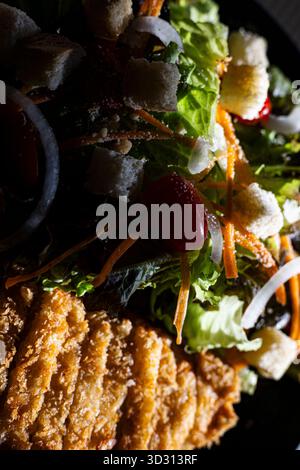 Crossup Fried Chicken Salad mit gemischtem Gemüse, Ein lebendiges Werbefoto von knusprigem gebratenem Huhn auf einem bunten gemischten Veggie Salat, perfekt für einen gesunden Stockfoto
