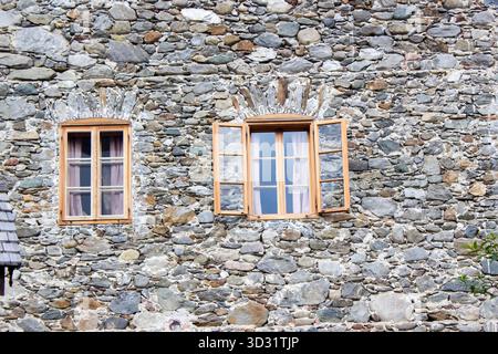 Altes Steingebäude mit kleinen Fenstern - Fassade mit altem Fenster, Österreich Stockfoto