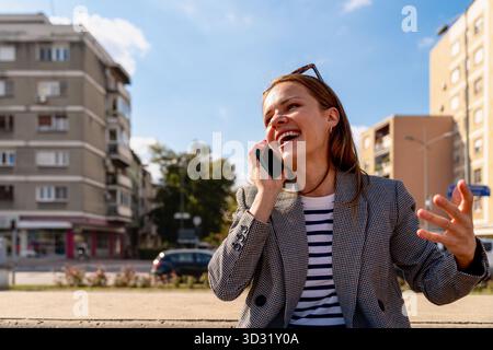 Glückliche Frau, die in der Stadtstraße telefoniert Stockfoto