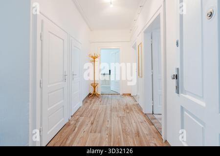 Heller Flur mit weißen Türen und Holzboden Stockfoto