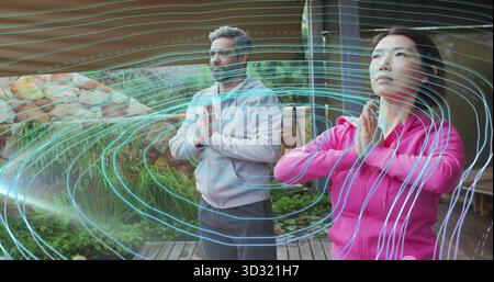 Beim Üben des Gebets stellen Mann und Frau in Sportbekleidung auf der Terrasse mit digitalem Energiefeld auf Stockfoto