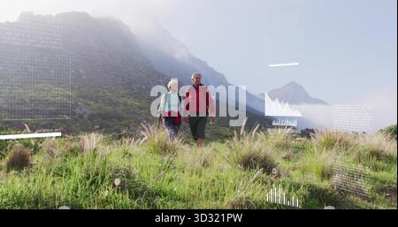 Trekking-Seniorenpaar in Lagenjacken und -Stiefeln, erkunden die Almwiesen mit Tagesrucksäcken Stockfoto