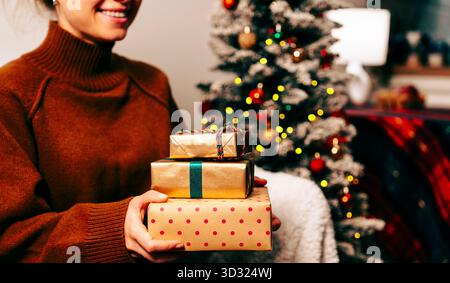 Lächelnde Frau, die zu Hause Weihnachtsgeschenke hält. Stockfoto