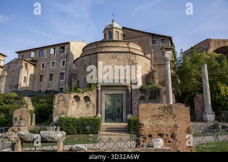 Der Blick auf den antiken Tempel des Romulus steht in markantem Kontrast zu den modernen Gebäuden unter klarem Himmel, Rom, Latium, Italien. Stockfoto
