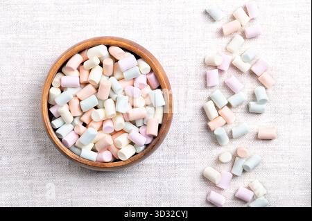 Mehrfarbige Mini-Marshmallows, in einer Holzschale, auf Leinen. Pastellfarbene kleine Stücke einer Süßwaren aus Zucker, Wasser und Gelatine. Stockfoto