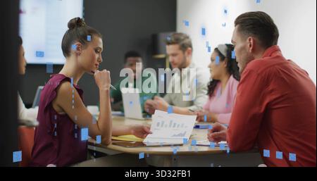 Kollegen, die gedruckte Karten und Daten auf dem Laptop im Besprechungsraum in formeller Kleidung mit Stiften überprüfen Stockfoto