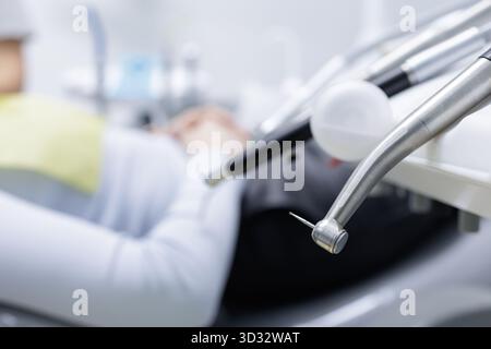 Nahaufnahme eines Hochgeschwindigkeits-Zahnhandstücks mit Bohrer auf der Bestrahlungseinheit in der Nähe eines Patienten, die die Behandlungsvorbereitung in einer modernen Klinik zeigt. Stockfoto