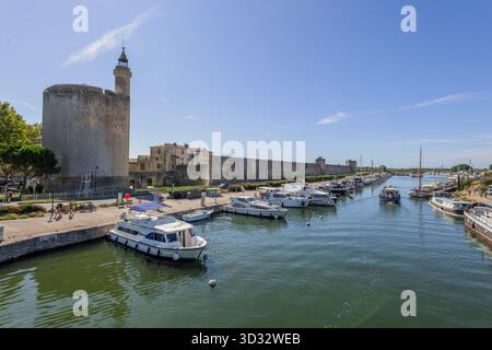 Blick über den Rhone-Sete-Kanal in Richtung des konstanzer Turms und der mittelalterlichen Stadtmauer in Aigues-Mortes in Südfrankreich. Stockfoto