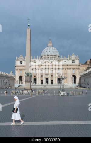 Nonne spaziert an einem dunklen, bewölkten Tag durch den Petersplatz und den Petersdom Stockfoto