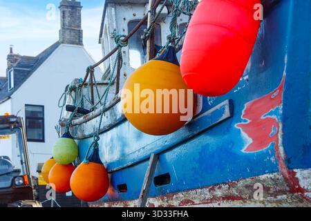 Nahaufnahme von farbenfrohen Plastikbojen, die an einem verwitterten Fischerboot hängen, das in der Nähe des Hafens von St abbs liegt, schottisch grenzt an schottland Stockfoto