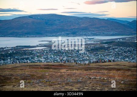 Blick von Storsteinen, Tromso, Norwegen, Panoramablick auf die Stadt eingebettet zwischen sanften Hügeln und einem großen Gewässer, mit Menschen auf einer h Stockfoto