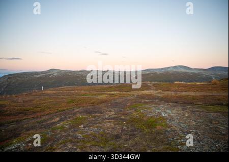 Storsteinen, Tromso, Norwegen, eine ruhige Landschaft im Morgengrauen mit sanften Hügeln und einem Flickenteppich aus Gras und Sträuchern unter einem sanften rosa Himmel Stockfoto