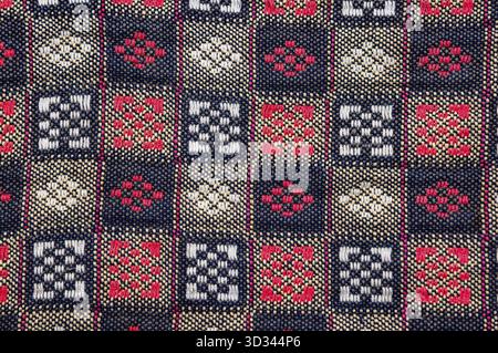 Nahaufnahme eines lebendigen Textils mit einem komplexen geometrischen Muster. Das Design zeigt sich wiederholende Quadrate mit detaillierten Motiven Stockfoto