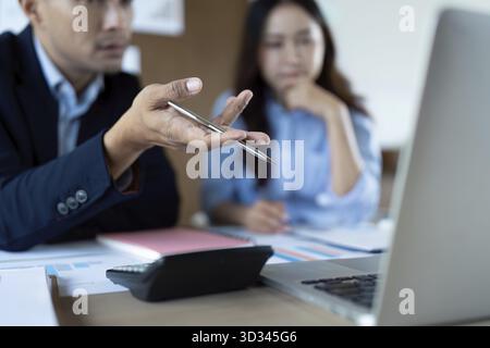 Zwei Fachleute führen ein fokussiertes Gespräch, während sie Daten auf ihrem Laptop analysieren und eine effektive Teamarbeit demonstrieren Stockfoto