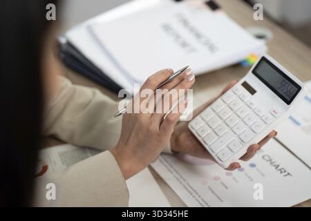 Eine professionelle Frau analysiert Finanzdaten mit einem Taschenrechner und bereitet sich auf ein strategisches Gespräch im Büro vor Stockfoto