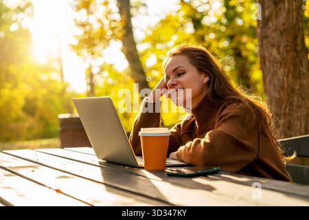 Moderne Frau, die an sonnigen Tagen im Park arbeitet oder studiert Stockfoto
