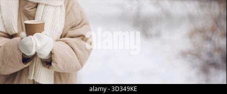 Weibliche Hände halten Kaffee-Heißgetränk-Tasse und genießen Winterwetter auf verschneiten Straßen Nahaufnahme mit Kopierraum-Mockup Stockfoto