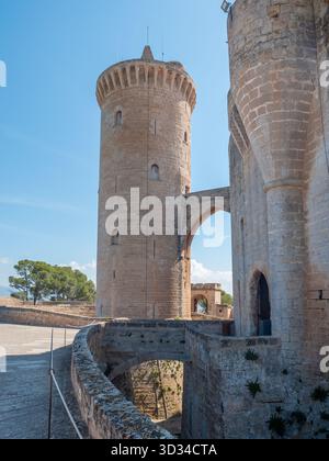 Castell de Bellver, Palma de Mallorca, historischer Steinturm mit einer Bogenbrücke verbindet zwei antike Gebäude unter einem klaren blauen Himmel, Mallorca Stockfoto