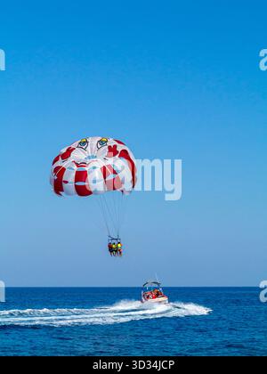 Touristen, die von einem Motorboot aus im Mittelmeer vor der Küste von Protaras im Osten Zyperns parasailing oder Parasailing. Stockfoto
